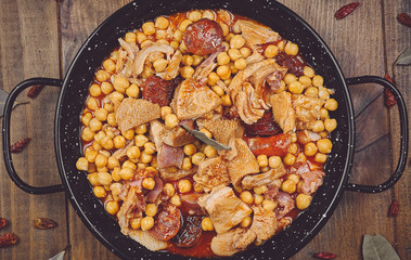 Garbanzos con callos en cazuela negra fondo madera