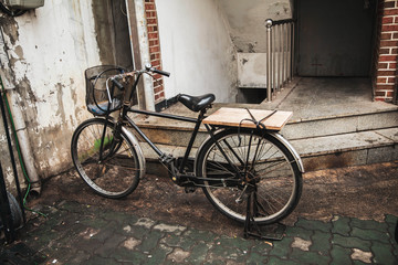 Fototapeta na wymiar Vintage old bicycle with basket and wooden back seat on the alley.