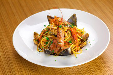 Plato de pasta italiana de marisco con mejillones y gambas sobre tabla de madera 