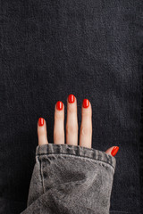 Open hand with red shiny manicure on a jeans background. Place for text