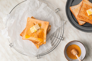Tasty toasted bread with honey and butter on white background