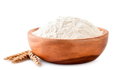 Pile of flour in a wooden plate with spikelets of wheat close-up on a white background. Isolated