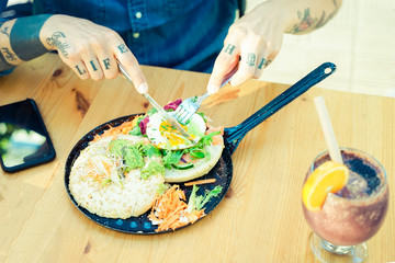 Man eating egg hamburger bread and vegetarian salad in the restaurant. Salad with egg, bread and carot. Young Eating food from a black pan. Food and dieting concept - Image