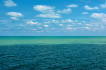 the sea surface is light turquoise and blue against a cloudy sky
