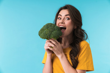 Positive young beautiful woman holding broccoli.