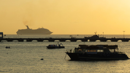 Barcos e navio em silhueta no por do sol