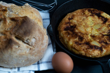 Potato and egg omelet in a frying pan with homemade bread