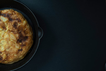 Potato and egg omelet in a frying pan on a dark background