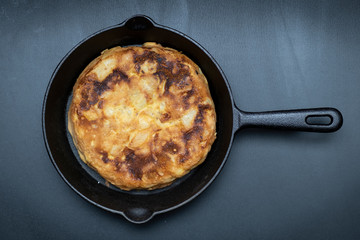 Potato and egg omelet in a cast iron frying pan on a slate base
