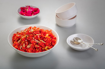 Gajar ka halwa is a sweet dessert pudding from India made from carrot, served in a bowl. Garnished with cashew, almond and pistachio nuts.