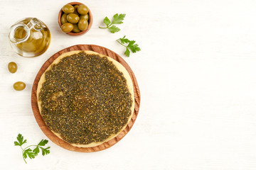 Zaatar manakeesh on wooden board with olives and olive oil  . Top view with copy space