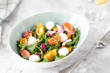 healthy salad with arugula with yellow and red tomatoes and mozzarella.