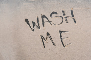 wash me text handwritten on the car vehicle during bad rainy weather season