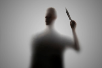 a dark silhouette of a dark person holding a knife, nightmare horror concept, out of focus blur
