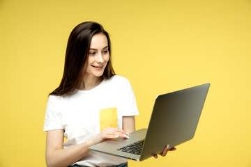 Naklejka premium woman with laptop on yellow background, copy space.