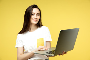 Naklejka premium woman with laptop on yellow background, copy space.