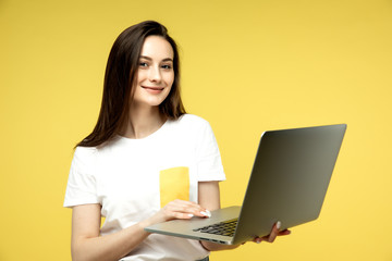 Naklejka premium woman with laptop on yellow background, copy space.
