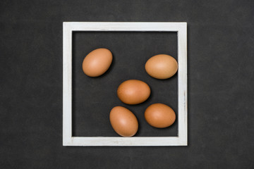 Eggs and white wooden frames composition on the fabric