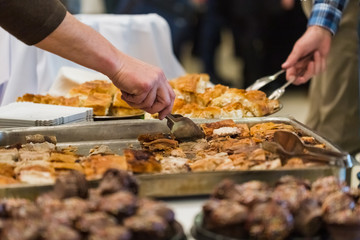 People serving themselves with food at restaurant event or business conference.