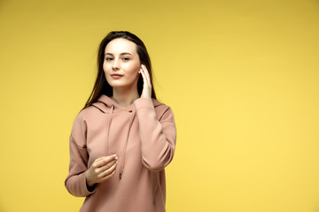 Energy girl with blue headphones listening to music on yellow background in studio. She wears white T-shirt, shorts. Long curly hair in tail is flying overhead from jump.