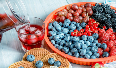 Different types of ripe berries - blueberries, raspberries, red currants, mulberries, a drink from berries and waffles with cheese. Appetizing snack with berries. 