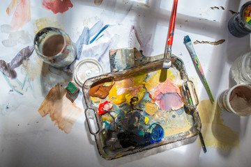 Palette and paint brush in artist hands. Artist paints oil picture with paint brush in hand palette...
