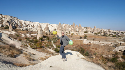 Young man with balloons celebrates his birthday in the Cappadocia desert, Turkey.