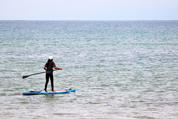 Sup surfing, girl with paddle standing on a board in open sea. Standup paddleboarding in SouthEast Asia