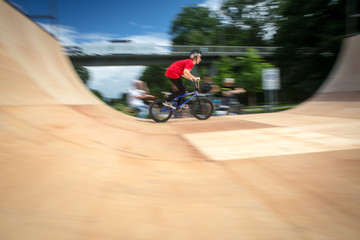  Bmx rider jumping over on a U ramp in a skatepark (motion blurred image)
