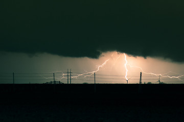 Lightning bolt at great distance. Dark clouds at night.