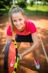 view of attractive young woman tennis player serving on a clay tennis court