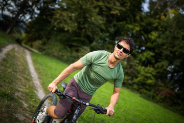 Fototapeta premium Young man riding his mountain bike outdoors on a forest path