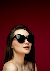 Fototapeta premium fashion model in sunglasses, beautiful young woman. lstudio shot, red background