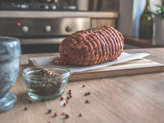 Uncooked spicy pork meat roulade prepared to roast, marinated with spices and herbs on a wooden plate.