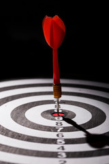 Close up shot red darts arrows in the target center on black background. Business target or goal success and winner concept