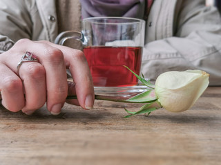 Female Hand with Limestone Ring holding White Flower in a Romance Date with a Cup of Tea on a restaurant Table