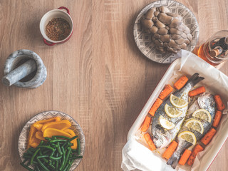 Raw dorado fish with spices lemon and vegetables, mushrooms cooking on baking tray.