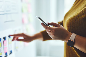 Close up of woman with mobile phone planning website on whiteboard