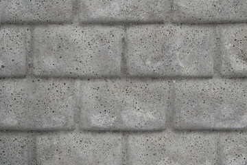 Gray cast concrete wall in the form of an imitation of masonry. Porous concrete with a structure in the form of bricks with small holes. Background