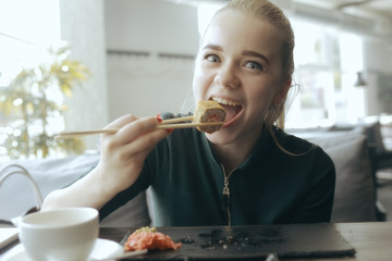 girl eats sushi and rolls in a restaurant / oriental cuisine, Japanese food, young model in a restaurant