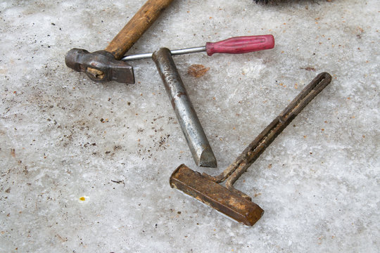 Old dirty tool: hammer, screwdriver, chisel, homemade rusty hammer wallow on ice in winter. A very scary repairman tool in Russia.