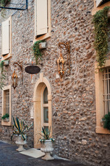 Fototapeta na wymiar Vertical picture of medieval stone narrow street in small italian town in Veneto with vintage lanterns and flowers in windows. Italia romantic travel tourism destination