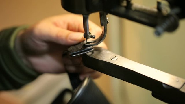 Shoemaker sewing on a sewing-machine. Close shot.
