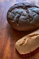 Ciabatta with olives and round rye bread with molasses on the old mahogany table.