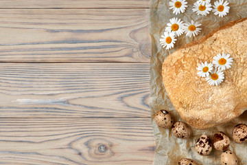 Homemade ciabatta in baking paper, quail eggs and chamomile flowers. Fresh diet healthy food in Italian tradition.