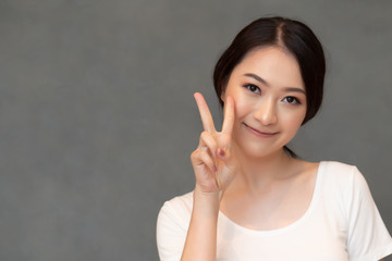 asian woman pointing two fingers; portrait of positive happy smiling southeast asian woman pointing up one finger, v for victory concept; asian Chinese adult woman model, casual theme