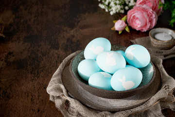 Unusual Easter on dark old background. Ceramic brown bowl with blue eggs.