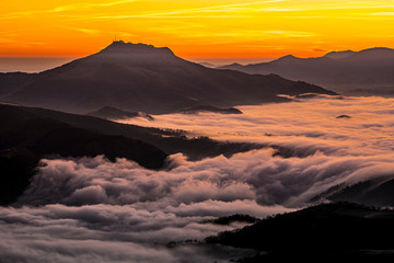 Fototapeta premium Detail of the beautiful Mount Larrun on a winter morning by the sea of clouds at the golden hour of dawn. Basque Country