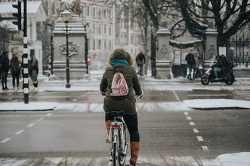 young woman on bicycle amsterdam street snow