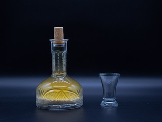 Vintage carafe with homemade vodka and the empty glass on the dark background. Alcoholic drink...